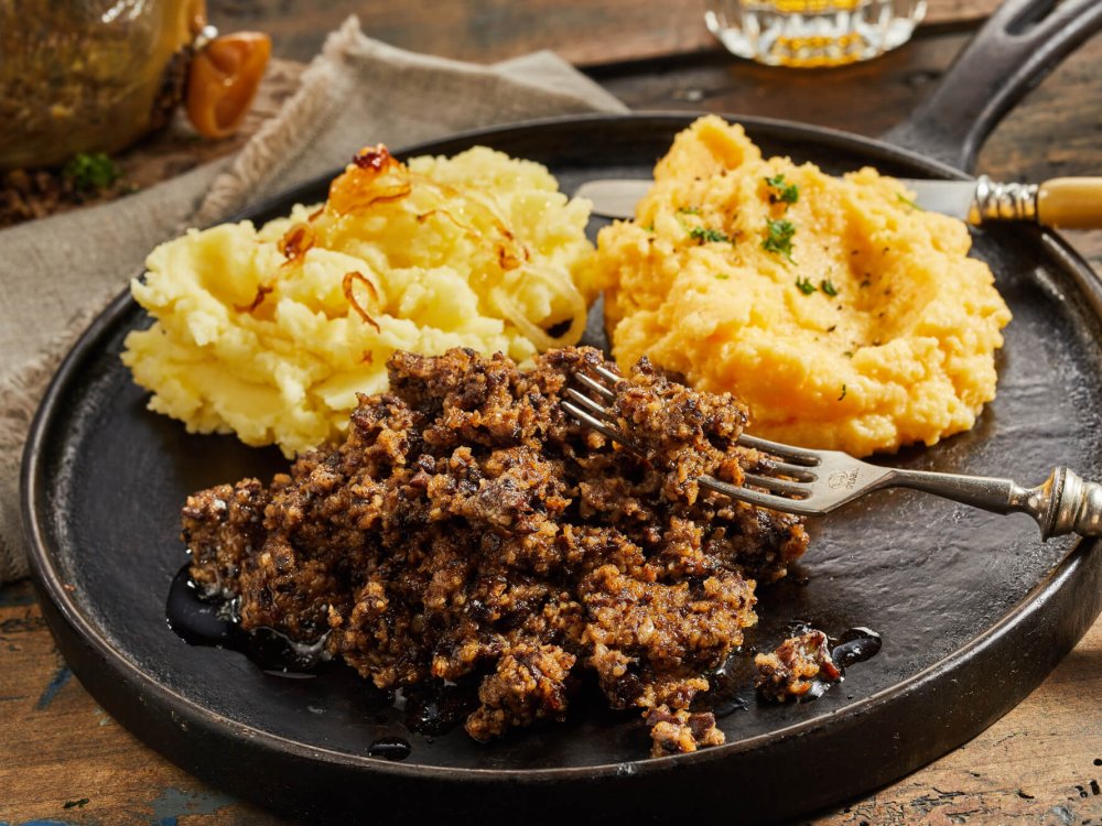 Rustic serving of haggis, neeps and tatties on a metal skillet showing the texture of the cooked meat with mashed turnip or swede and potato